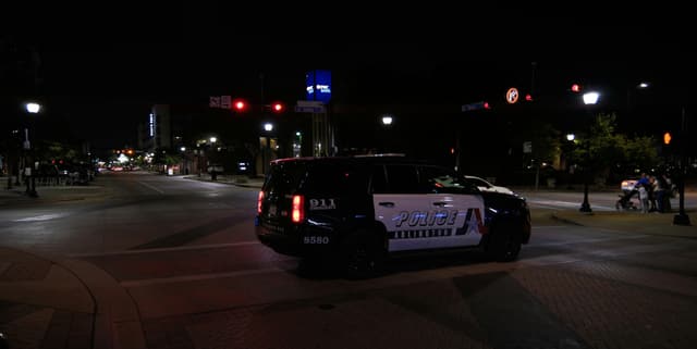 Police car driving on a city street at night.