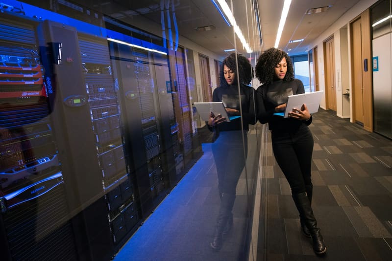 Two engineers reviewing tablets in a blue-lit data centre aisle